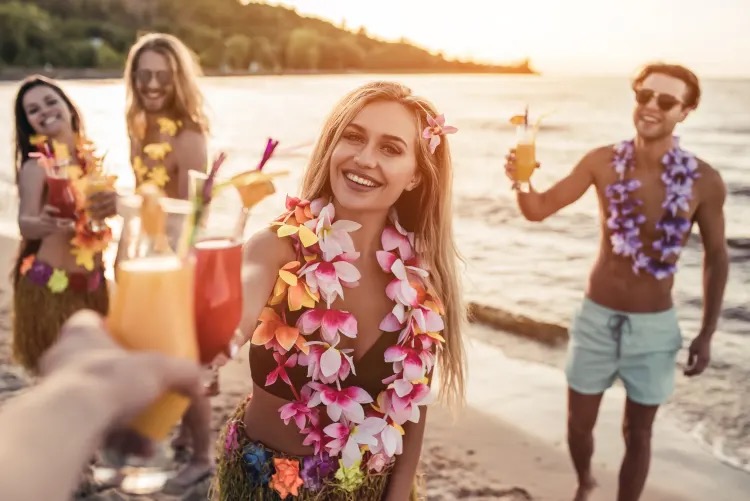 Friends having fun and drinking cocktails on the beach