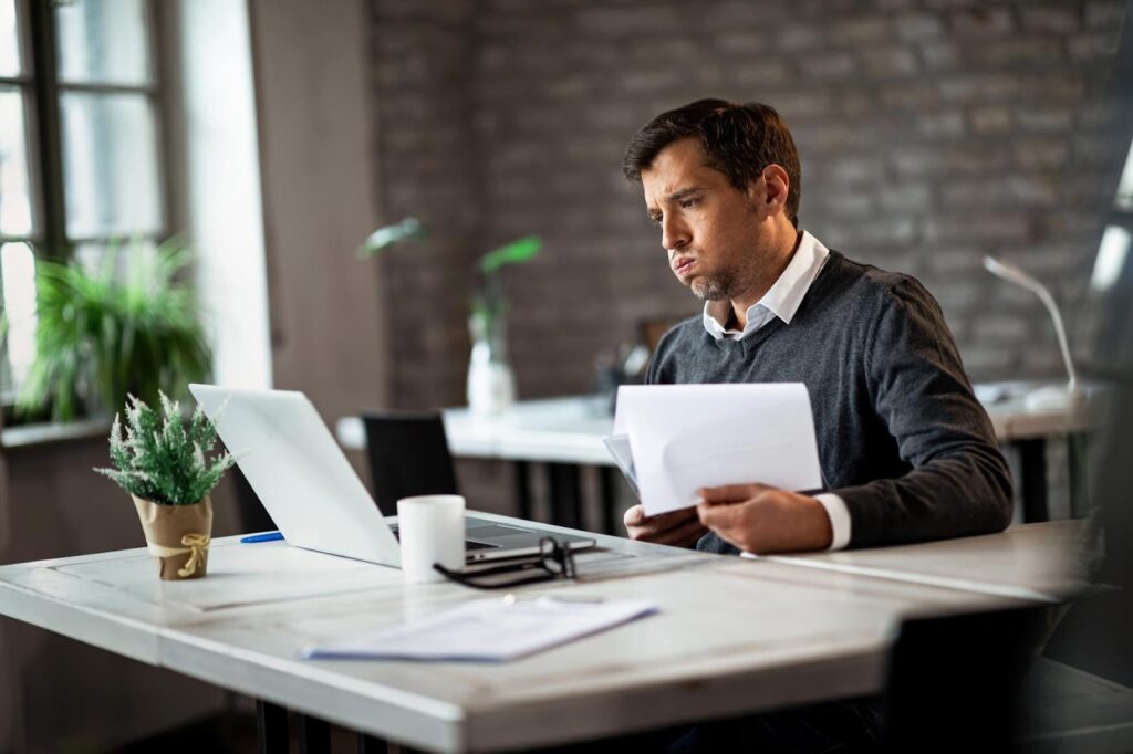 Man using laptop while going through business reports and working in the office