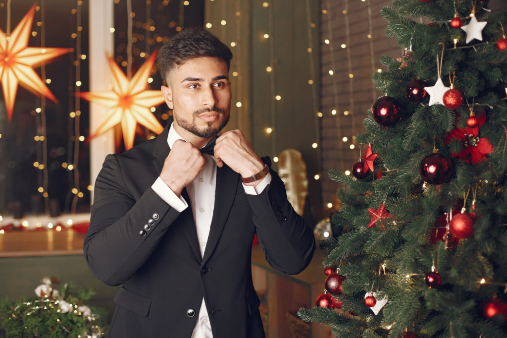 A man in a black suit near a Christmas tree